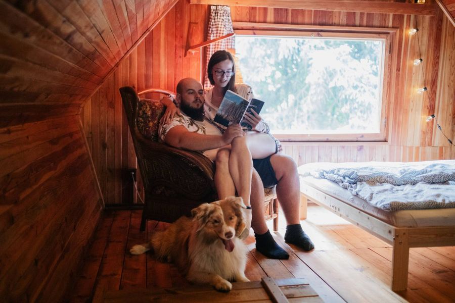 Pár si čte v křesle v podkroví, u nohou leží pes